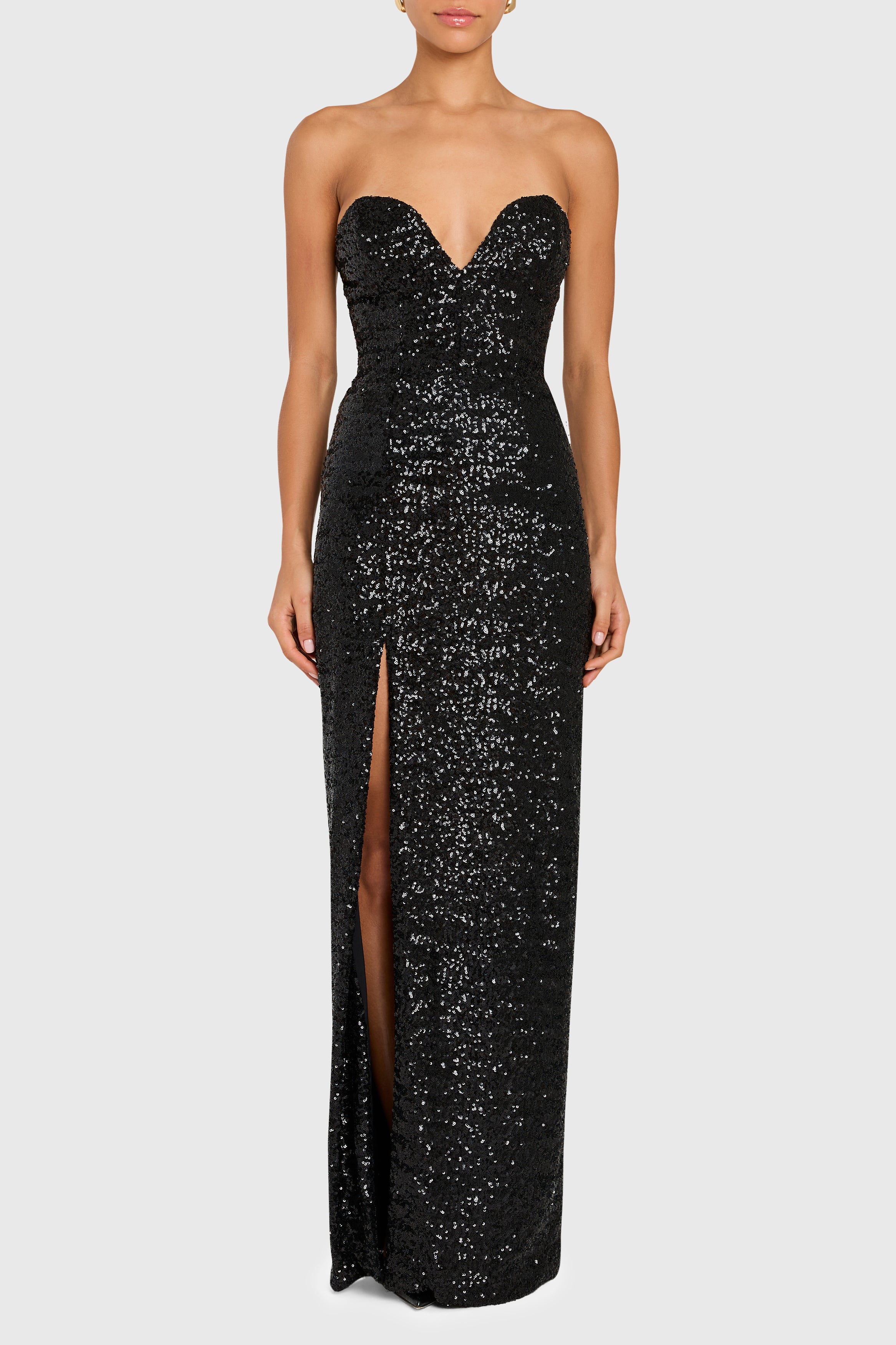 Black sequin strapless gown with a high slit on a white background