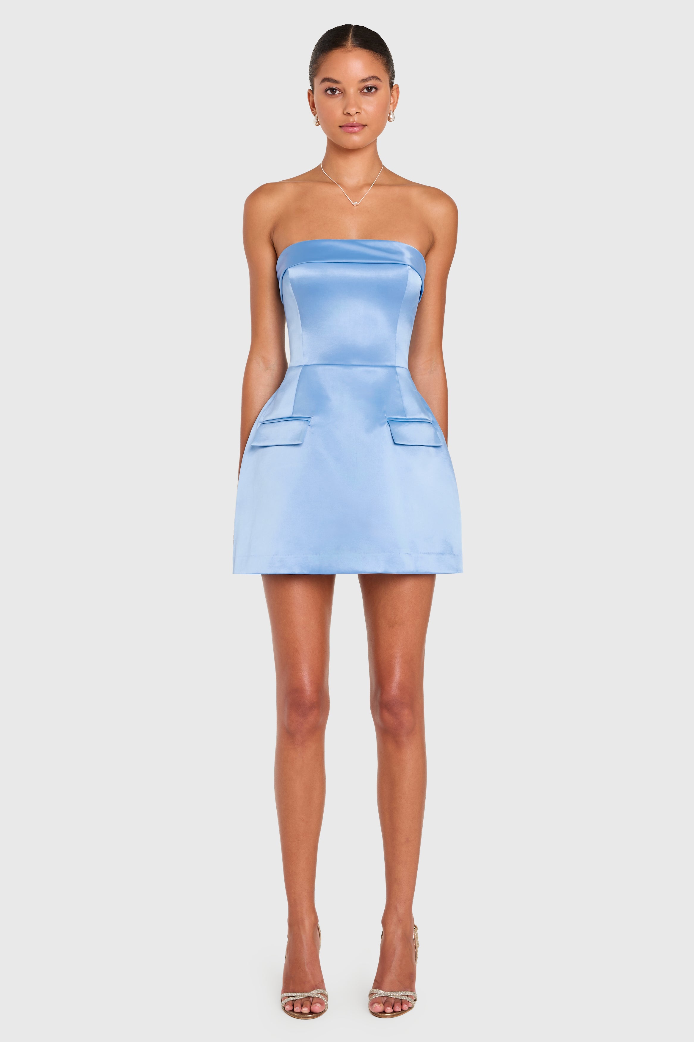 Model wears a blue satin mini dress on a neutral background. 