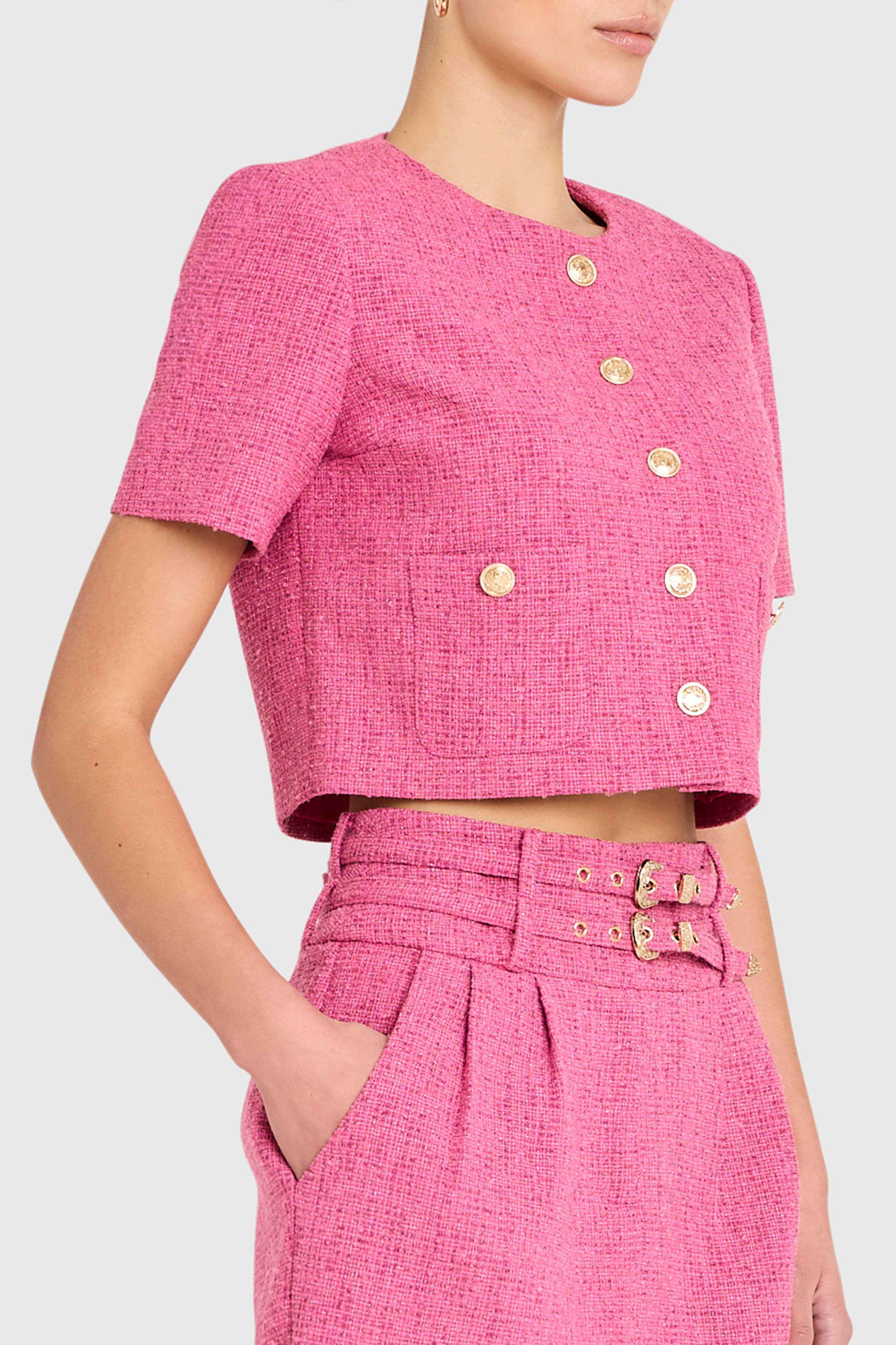 Pink textured outfit with gold buttons on a white background