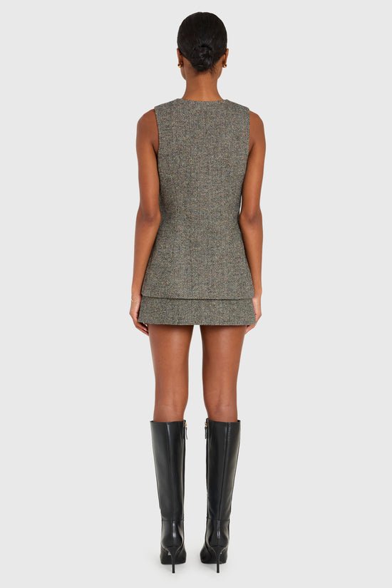 Person wearing a sleeveless gray dress with a plain background view 2