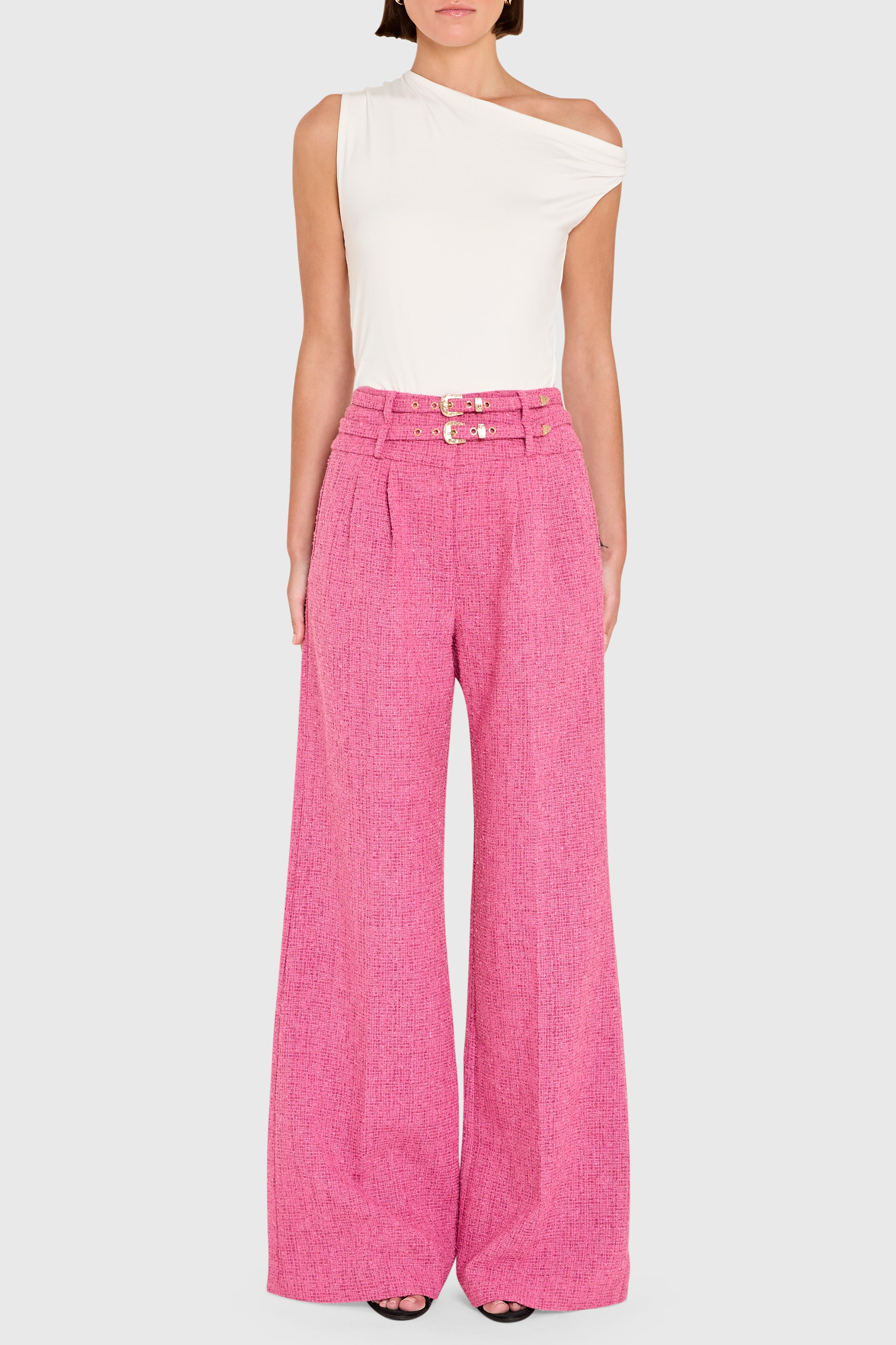 Person wearing a white sleeveless top and pink high-waisted pants on a white background