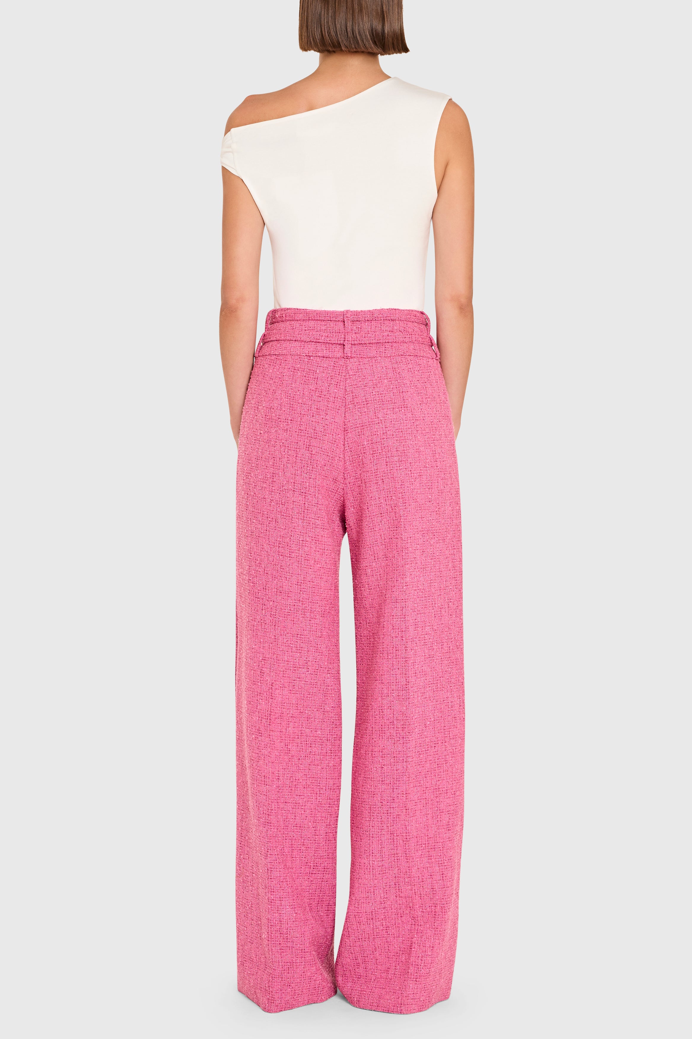 Person wearing a white sleeveless top and pink high-waisted pants on a white background