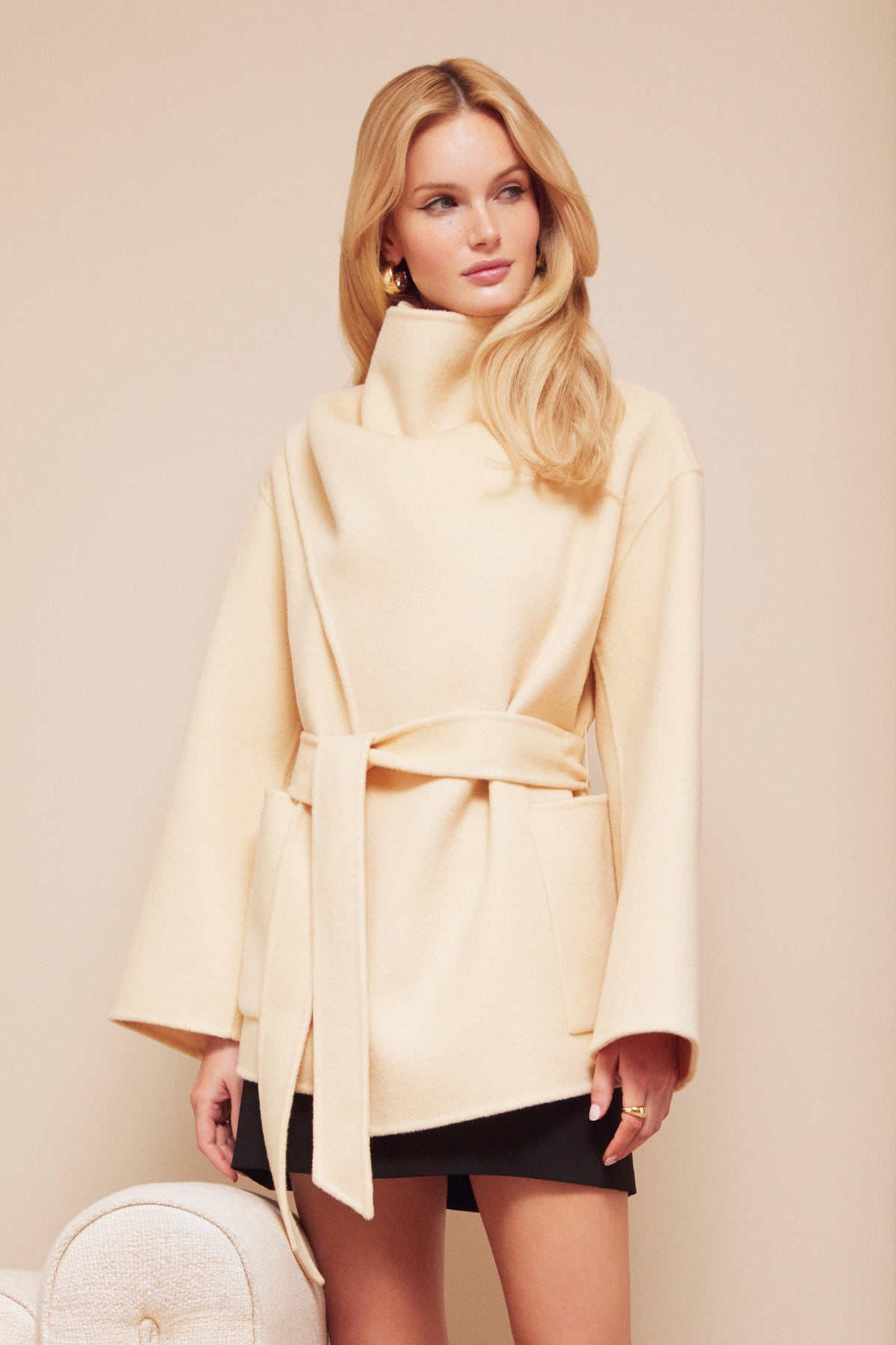 Woman wearing a light yellow coat against a beige background